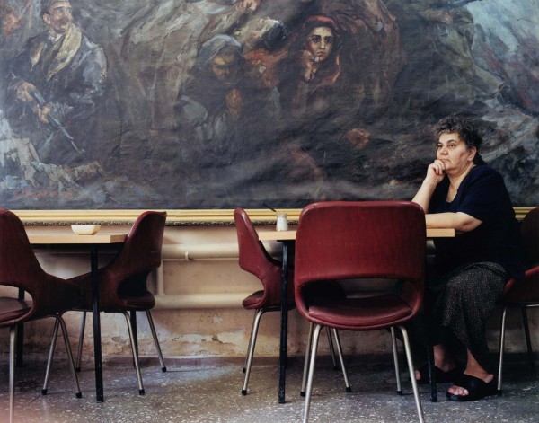 Александра Бакланова в греческом общинном центре в Ташкенте на фоне картины, изображающей коммунистов во время гражданской войны в Греции